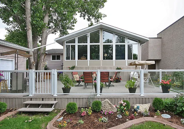 Solarium 4 saisons blanc avec de grandes fenêtres installé sur une terrasse dans un jardin